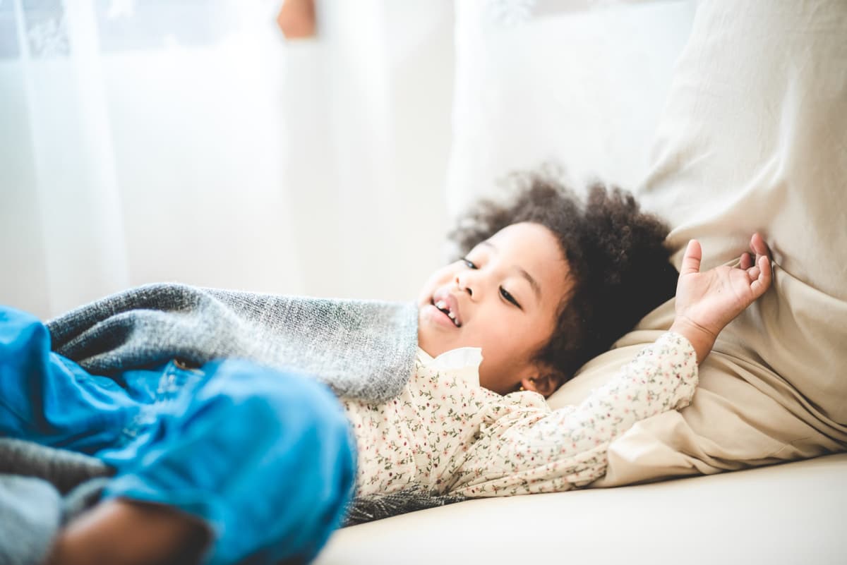 A young child laughing while lying on a sofa